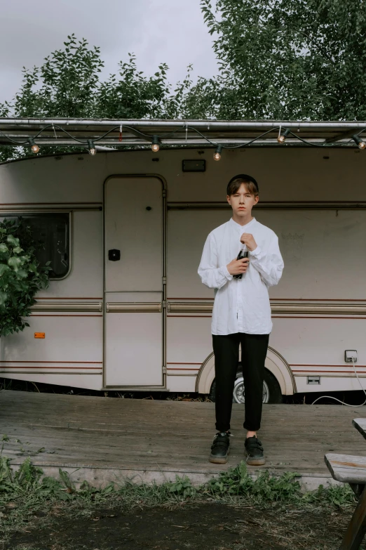 a man standing in front of a camper in front of trees