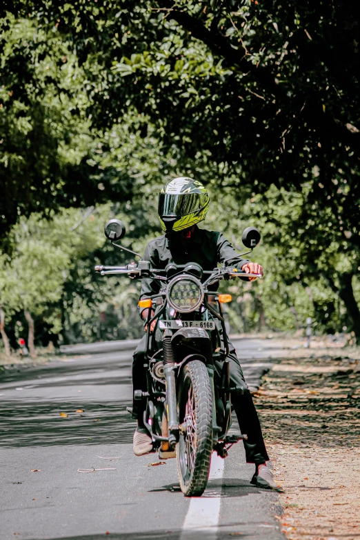 the motorcyclist is traveling down the street in his helmet