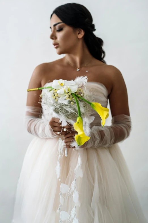 the bride in white holding yellow flowers is posed