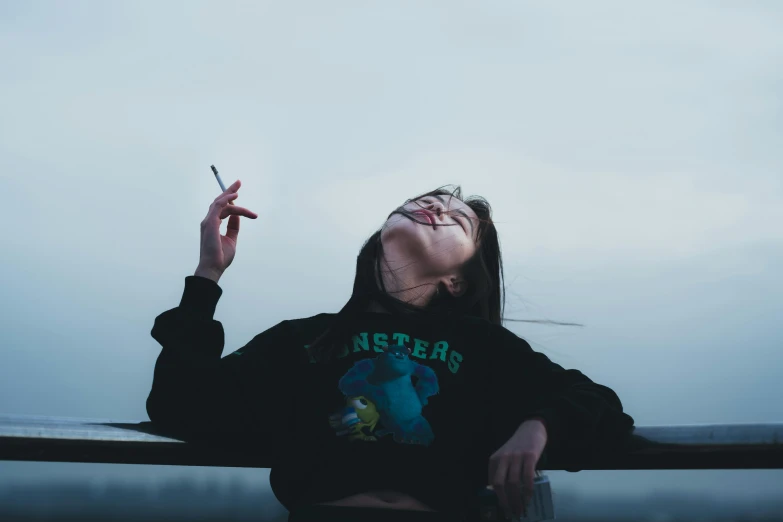 a person wearing an oversized black sweatshirt is smoking a cigarette