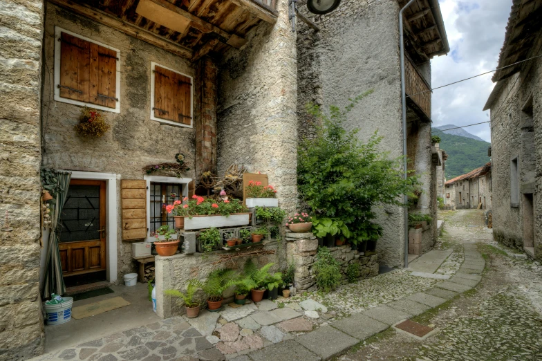 a stone house with a wooden door and shutters on a stone paved sidewalk in the countryside