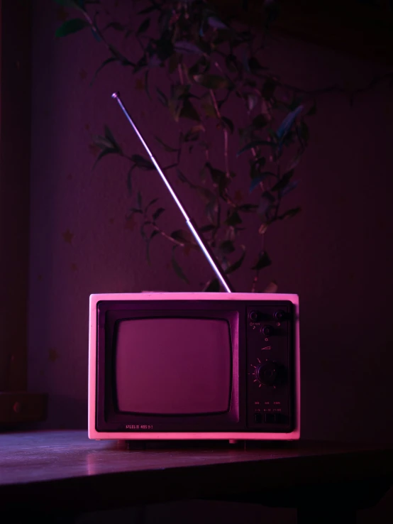 an old tv with a purple light on it is sitting on a table