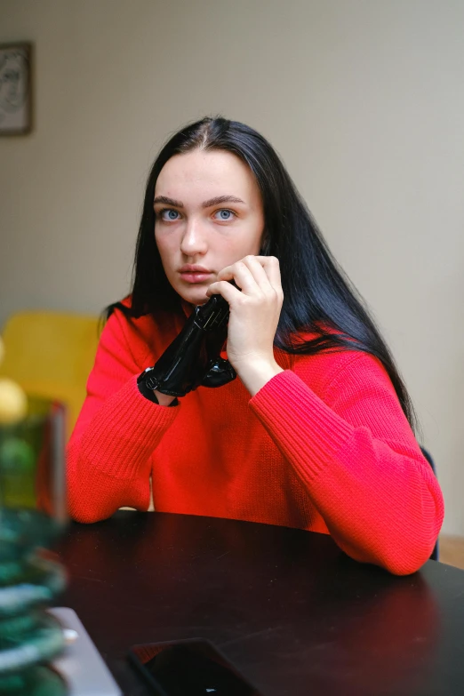 a woman in red shirt talking on phone sitting at a table