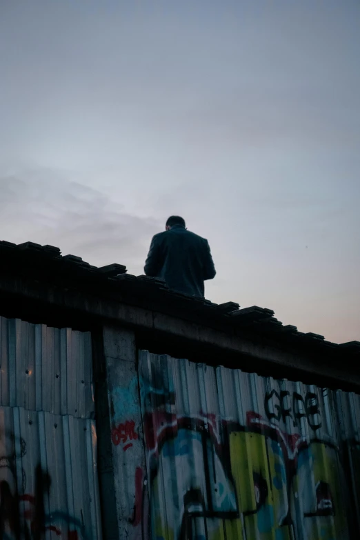 a man is on top of a fence with graffiti