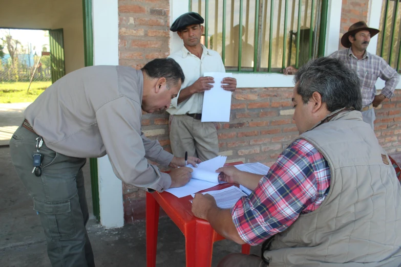 a man sitting down in a chair signing a sheet of paper