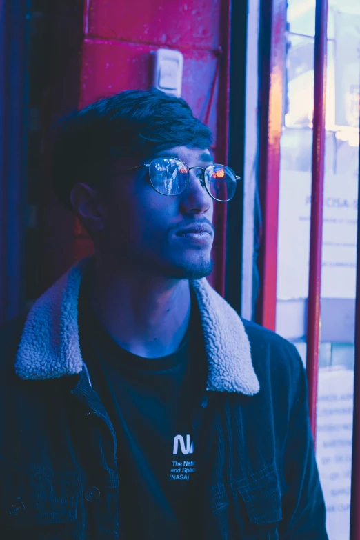 a man with glasses posing for a po in front of a building