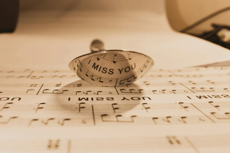 a tiny plastic pin with words on it sits on musical sheet paper