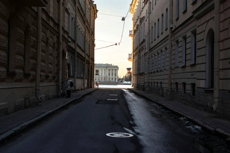 a deserted street in an old city, with cars passing through