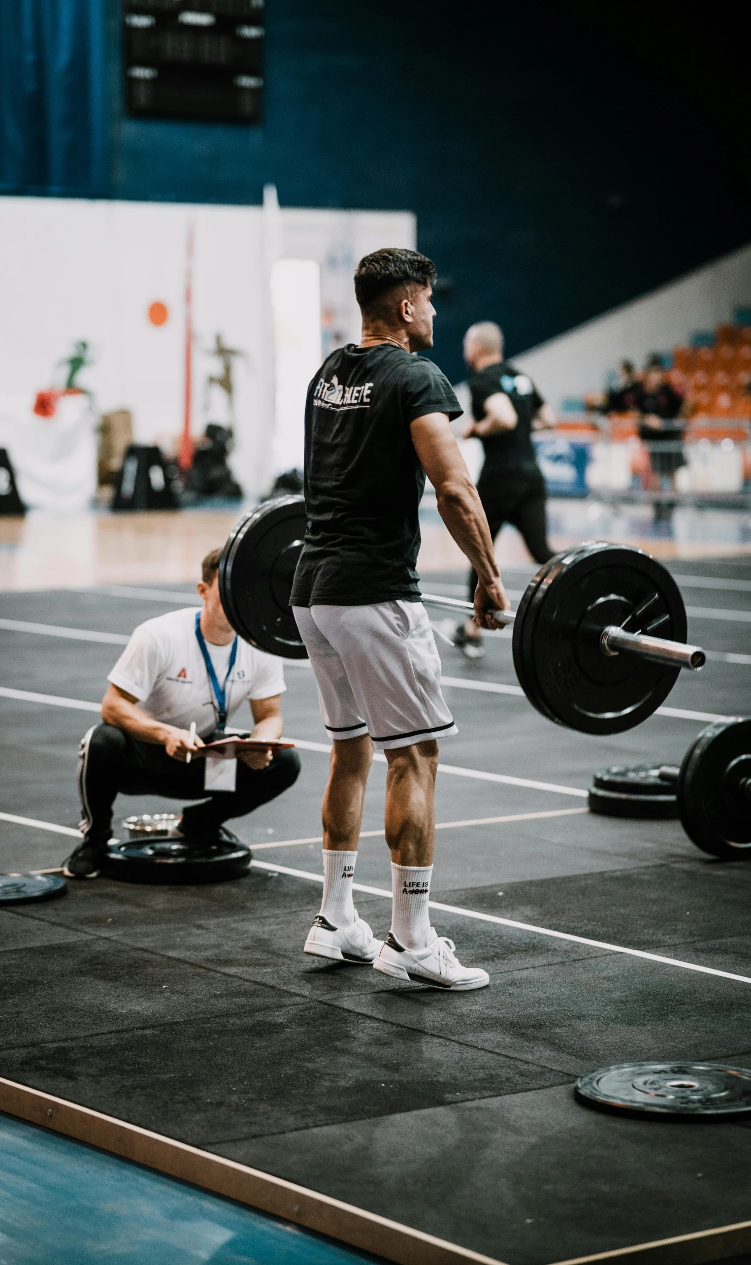 a man standing on top of a floor next to a barbell