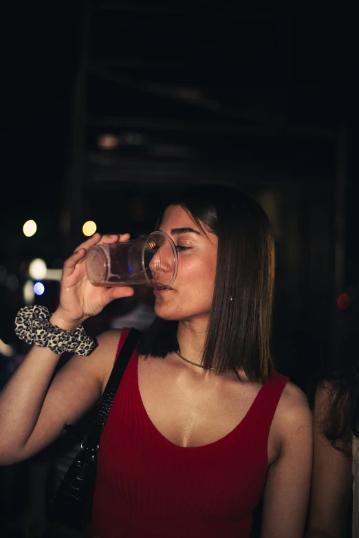 a girl drinking from a glass in a dark room