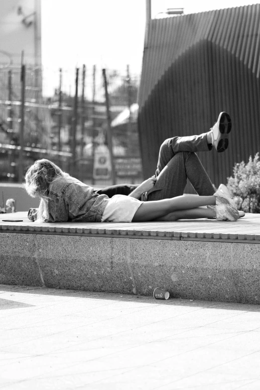 two people are laying on a sidewalk near flowers