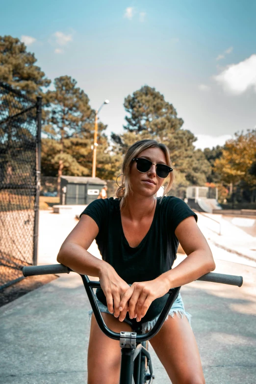 a girl wearing dark sunglasses rides a bicycle