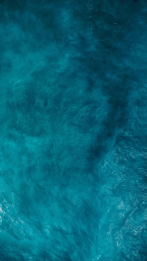 an overhead view of blue water and white boat