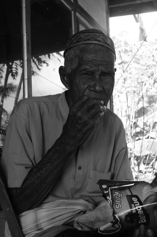 a man smoking a cigarette and leaning up against a fence