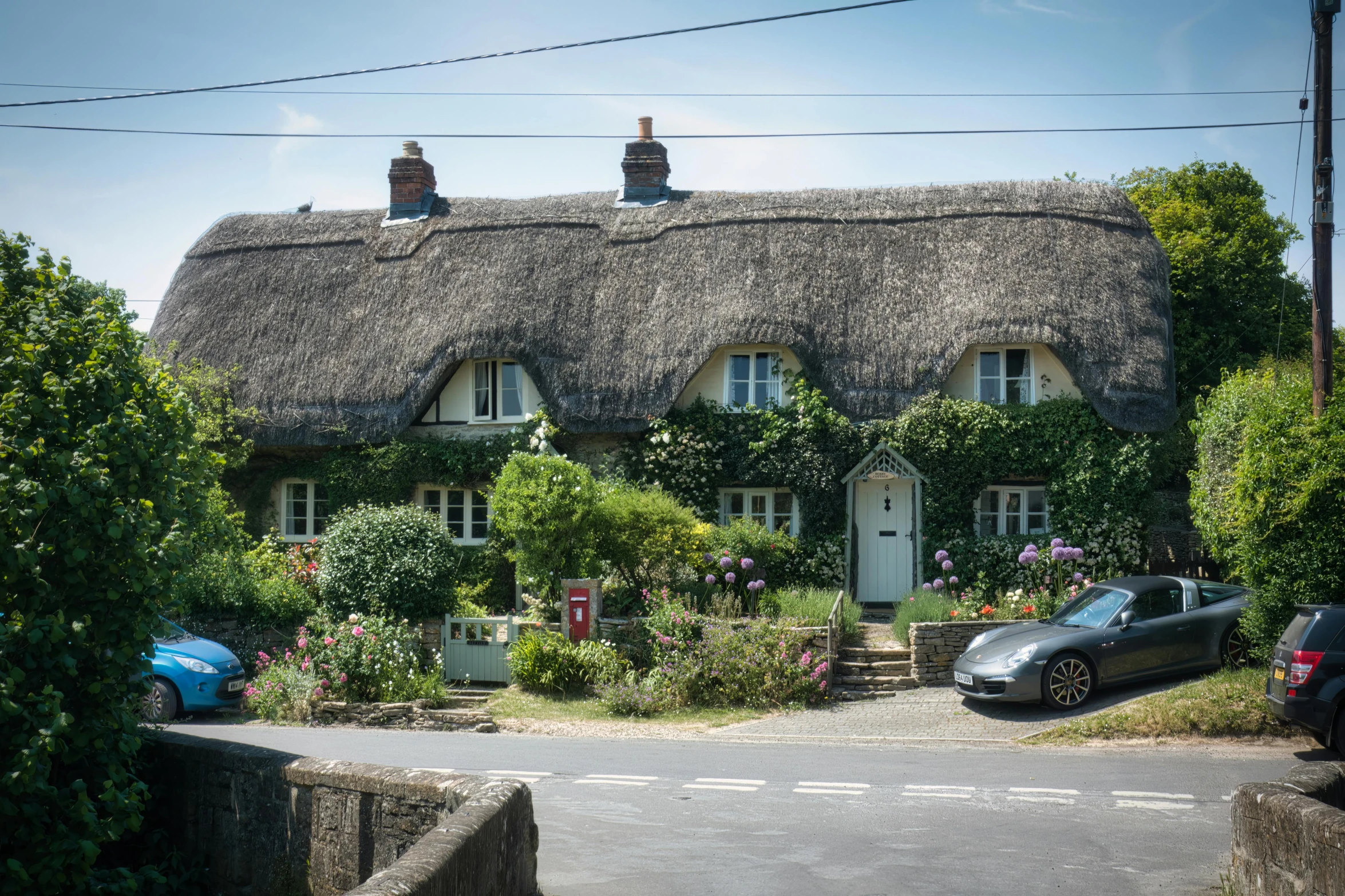 a large thatched roof home with two cars parked by the driveway