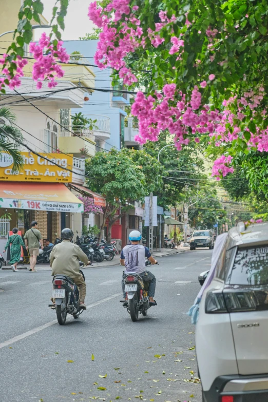 two men riding motorcycles down a street in front of cars