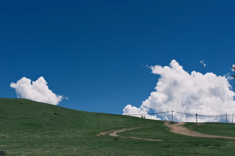 a hilly field under cloudy sky and power lines