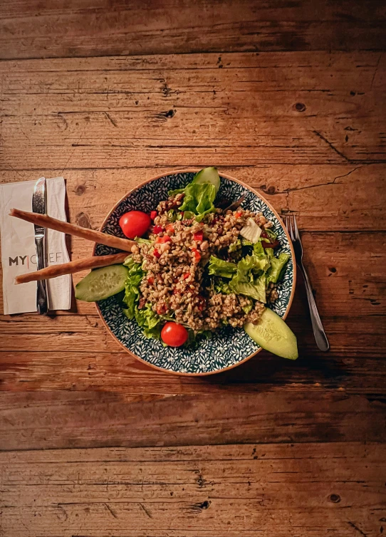 the salad has two wooden chop sticks in it