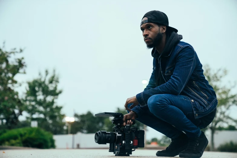 a man is crouching with a camera and on the ground