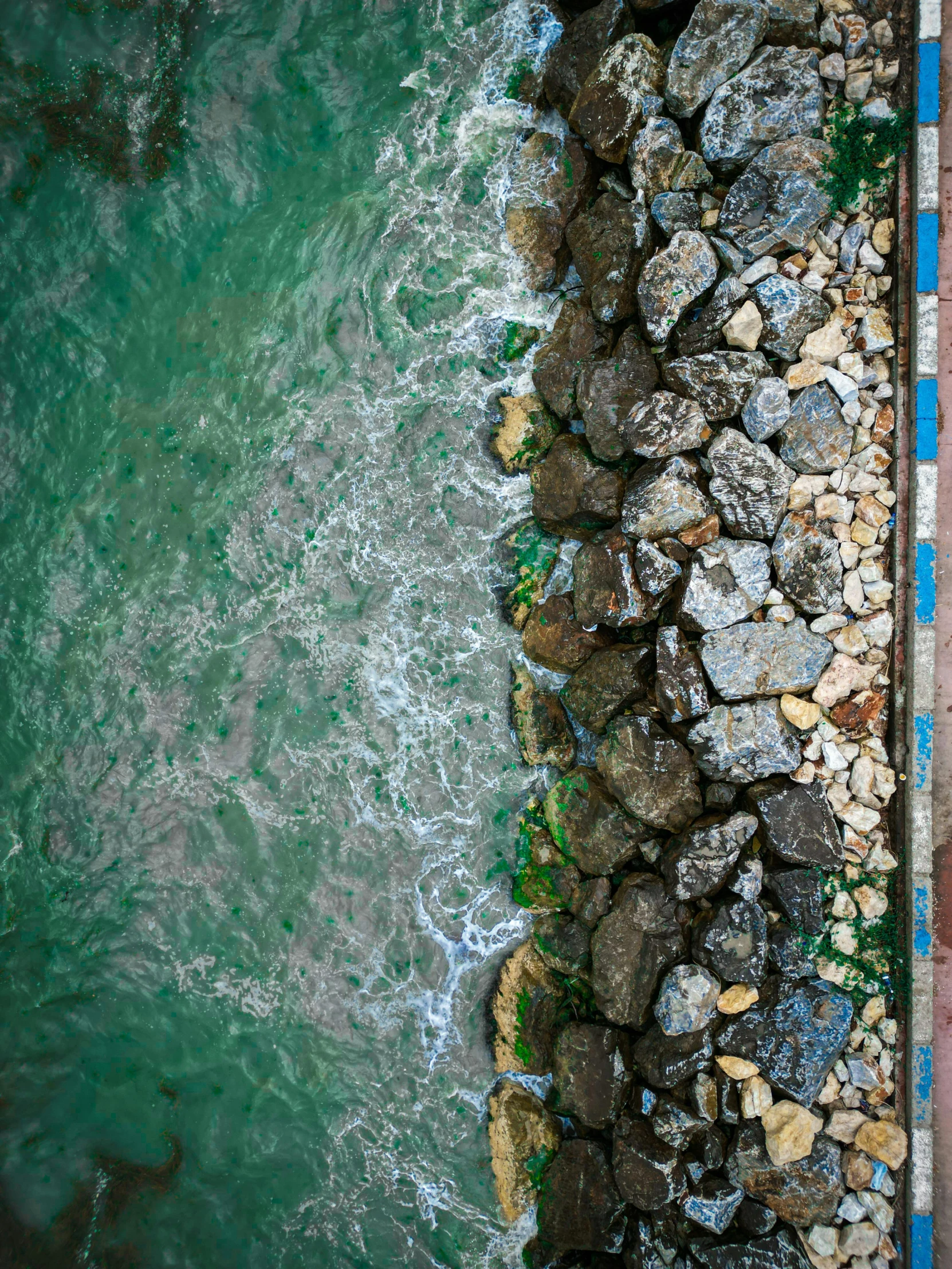 a walkway along the edge of the water is near rocks and gravel