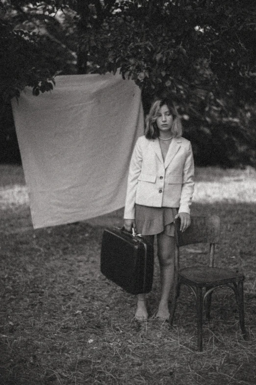 a girl in shorts holding a suitcase and a suit case in the grass