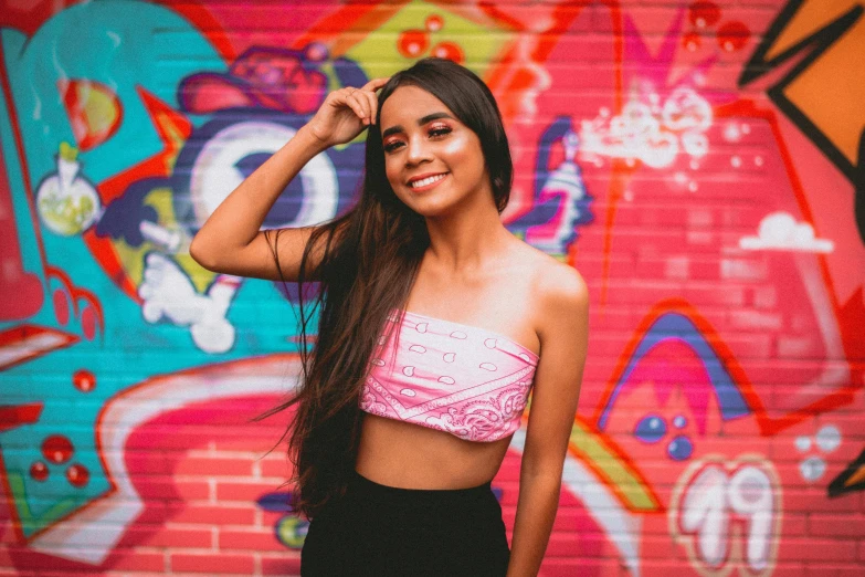 a woman wearing a pink crop top in front of graffiti