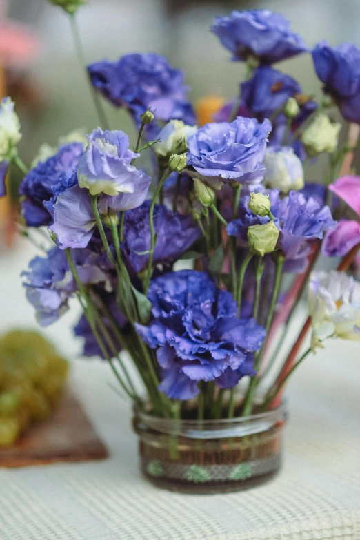 small purple and white flowers are in a glass jar