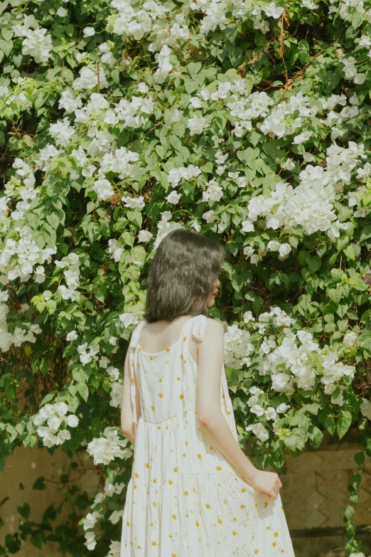 there is a woman standing in front of a wall with flowers