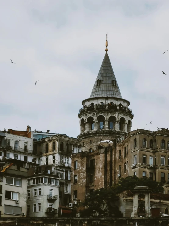 a very old tower with a lot of birds flying by