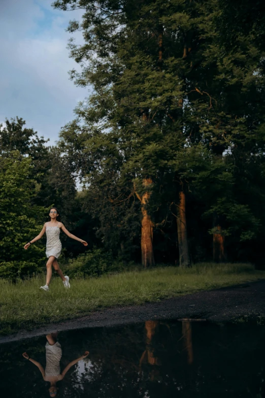 a woman running through the grass, with trees behind her