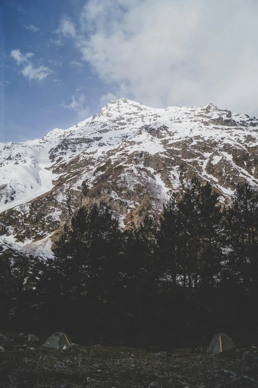 a large snow covered mountain with two tents under it