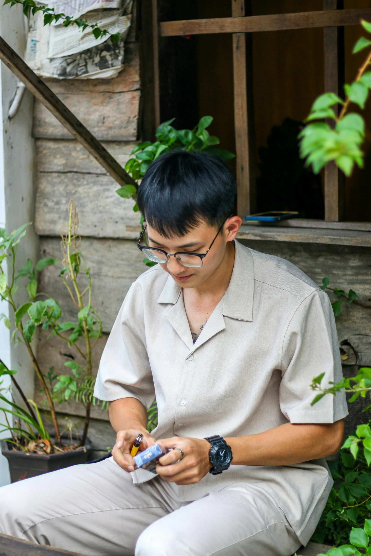 a young man sits on the ground holding a smart device