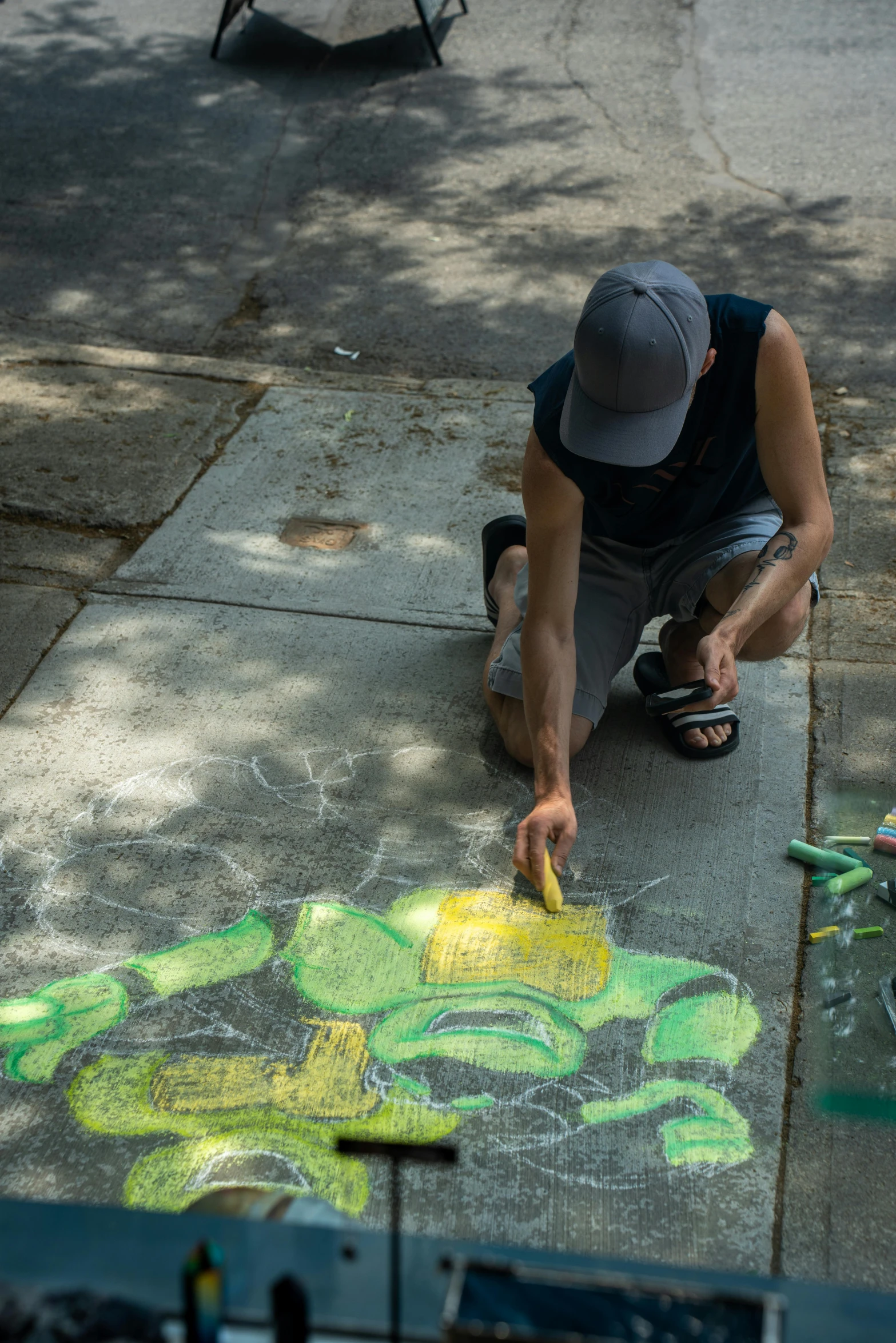 a man on the sidewalk writing and drawing on concrete