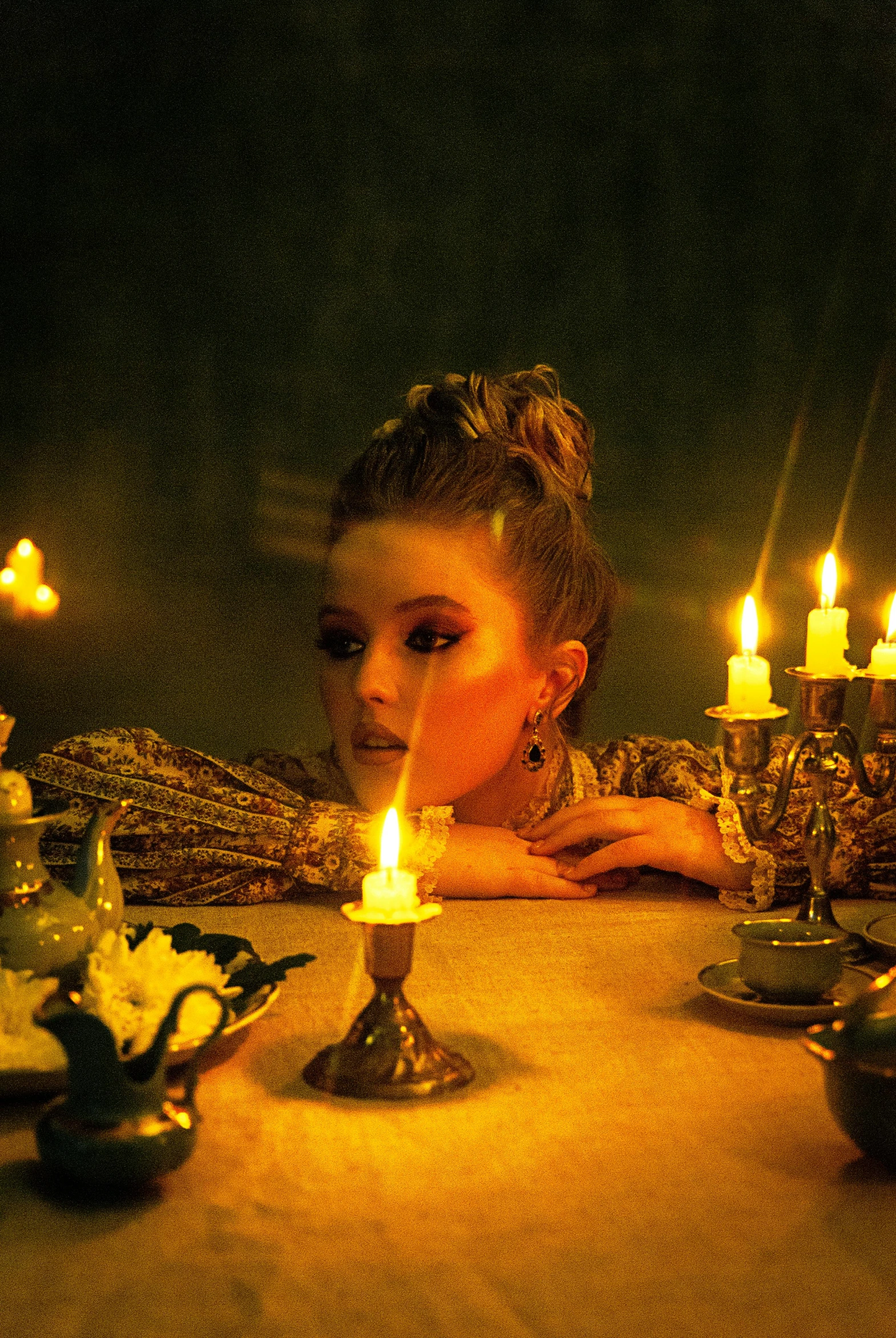 a woman that is sitting in front of a table with candles