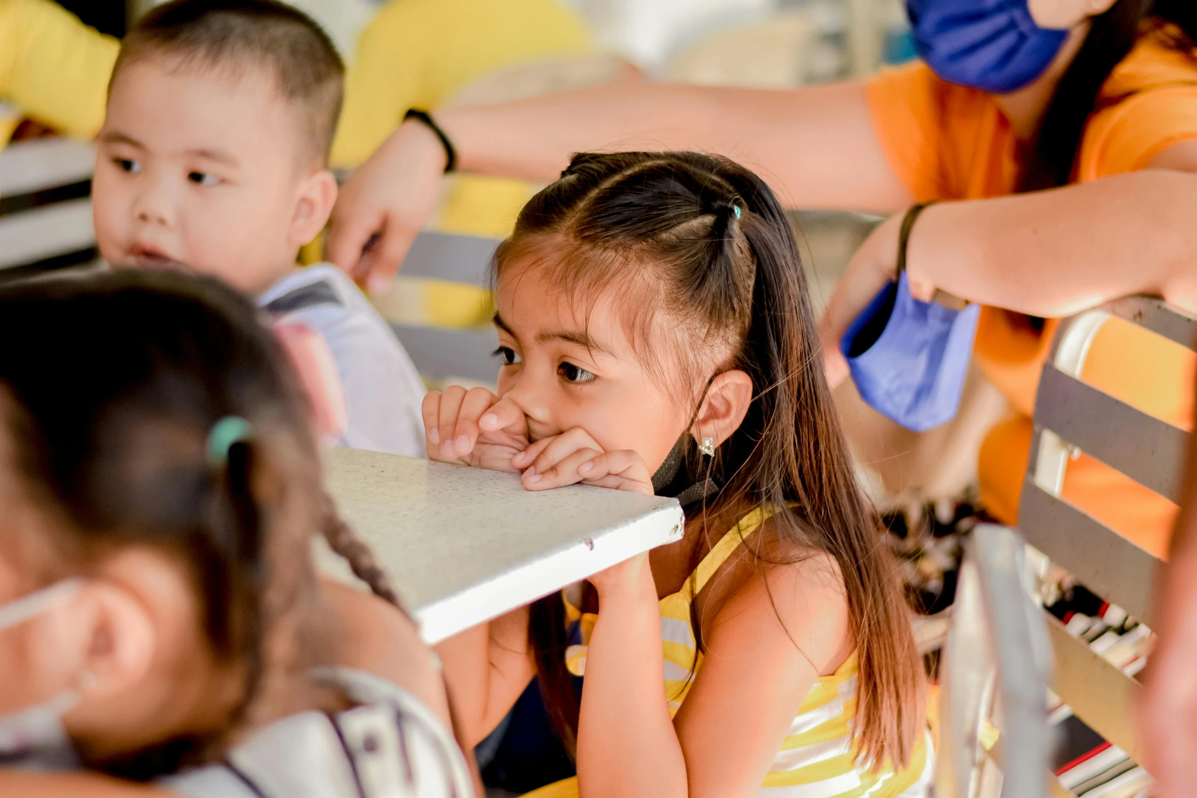 a  looking over a book with other children around her