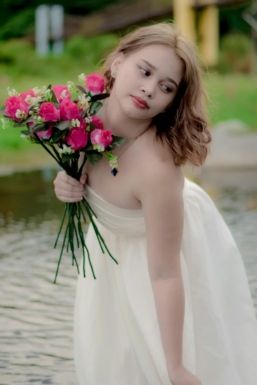 a young woman holds a bouquet of flowers in one hand and looks into the camera with a third hand behind her