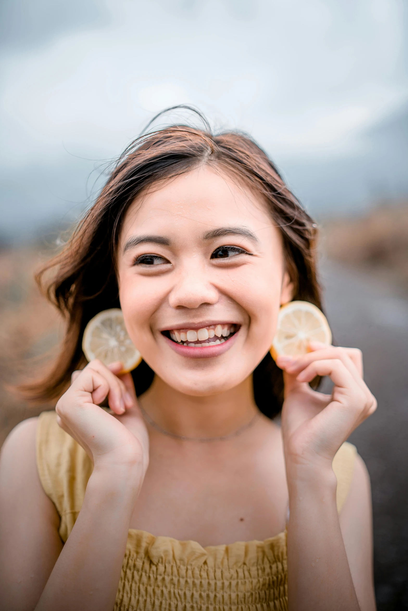 a woman smiling while holding up two lemons