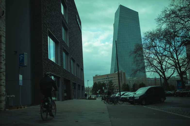 people on bicycles ride past tall buildings next to traffic