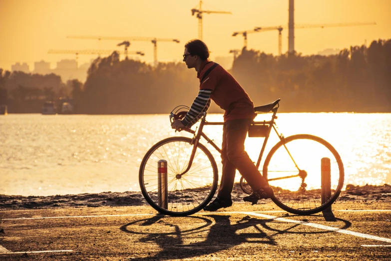 a woman wearing glasses riding a bicycle at sunset