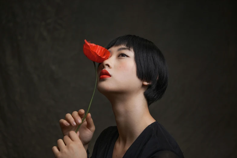 a woman is holding a flower in her face