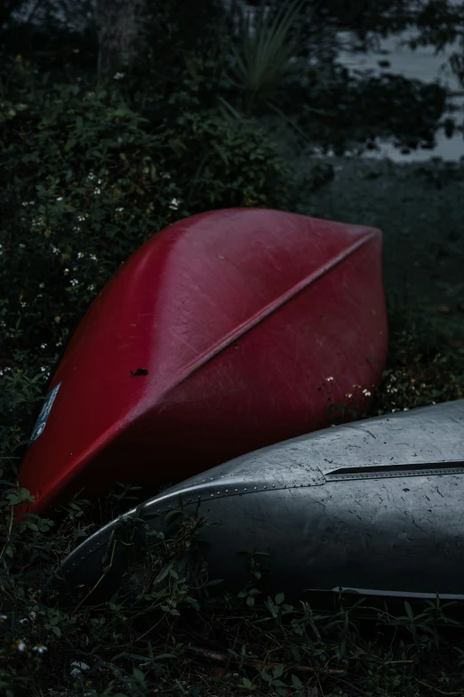 two canoes and a kayak laying in a grassy area