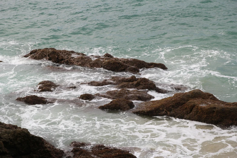 waves splash over rocky shoreline as the person watches