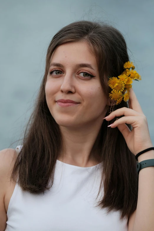 a young woman holding a yellow flower over her ear