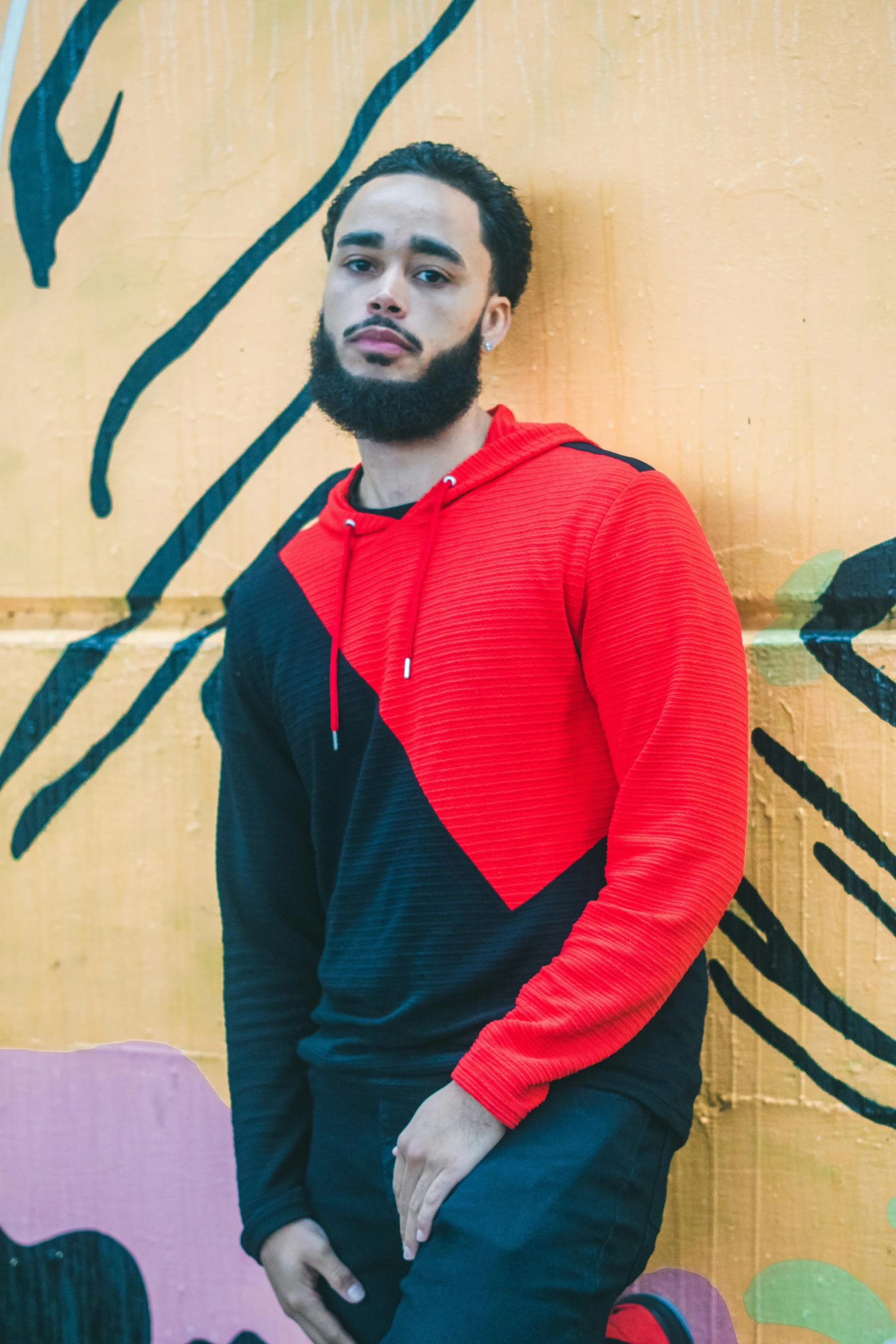 a man posing for a po in front of a graffiti wall