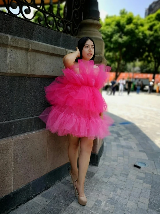 a woman in a pink tutu skirt posing near a building