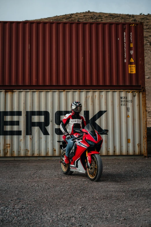 the motorcyclist is riding his bike next to the storage container