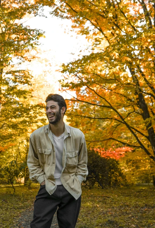 a man with his hands on his hips sits on a skateboard in a park