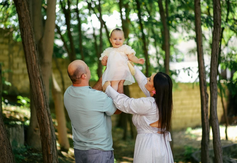 man and woman standing in front of a tree filled forest with a baby