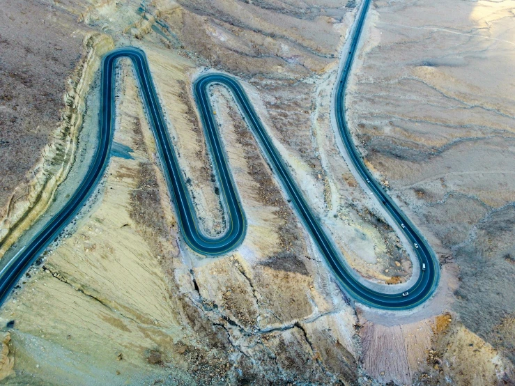 a winding road in the desert surrounded by sand