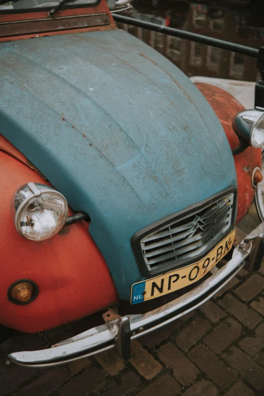 the old blue and orange beetle is parked in a parking lot